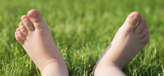 Childs feet lying in grass - Children’s Podiatry Sunshine Coast