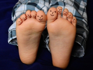 close up childs foot with marker faces drawn on