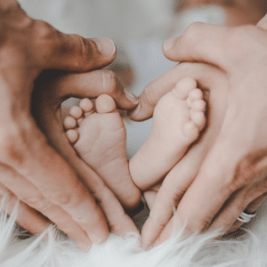 man and woman holding babies feet in heart shape